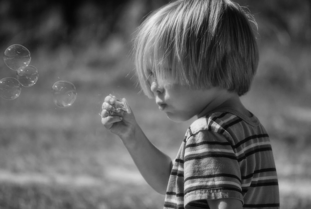 Little boy blowing bubbles; self-care activities for kids