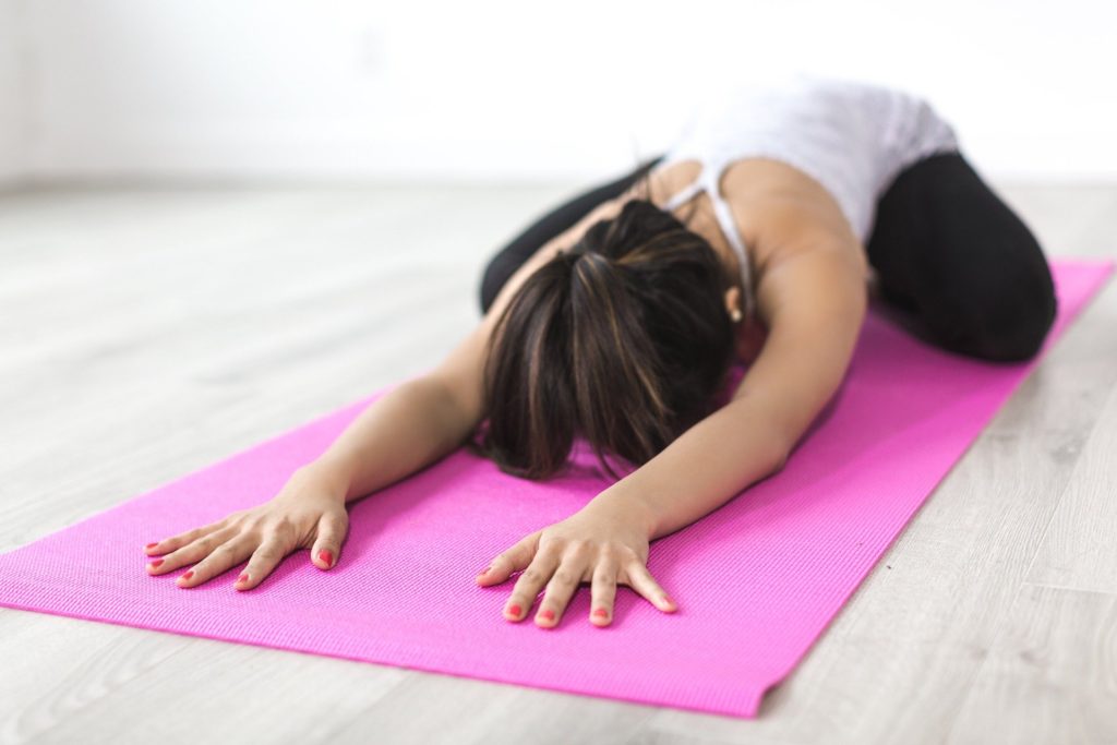 Woman practicing child's pose yoga pose; self-care activities for women